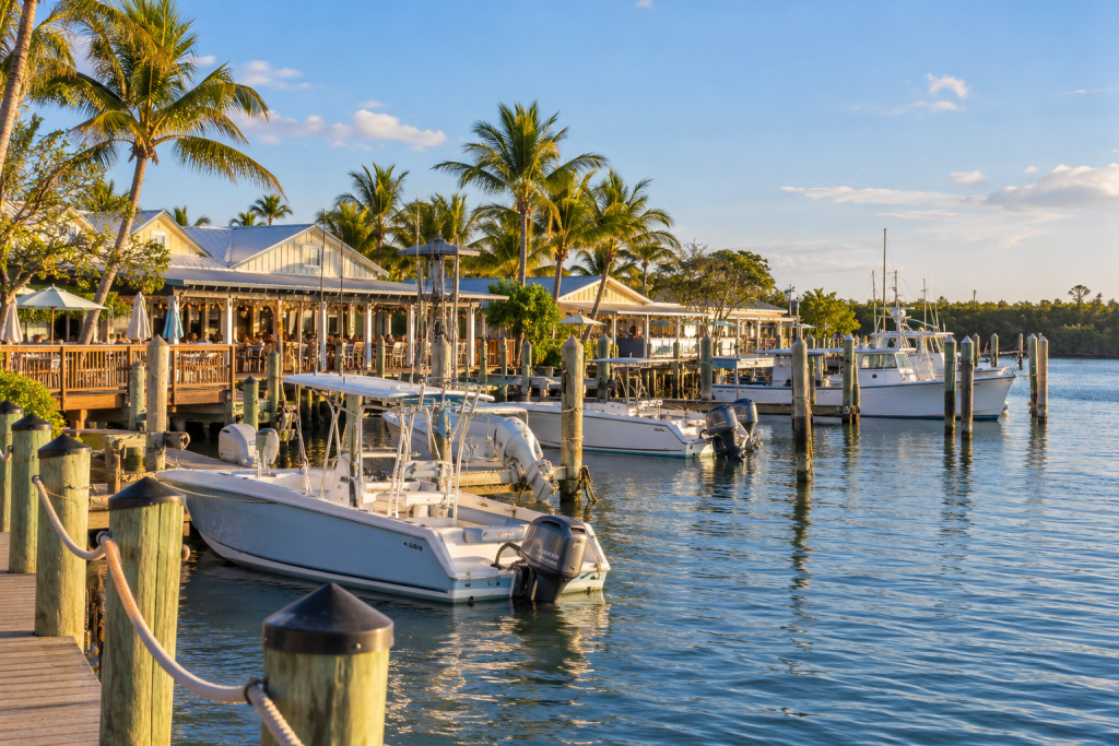Fishing boats docked beside palm-lined waterfront restaurants in a coastal Florida village.